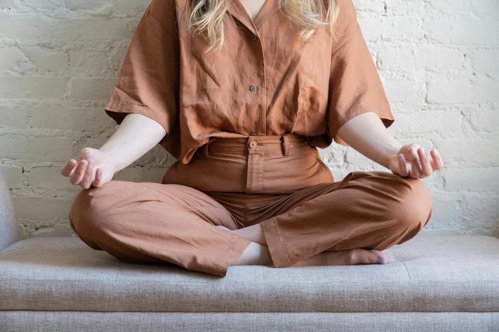 Pessoa meditando sentada no sofá de casa